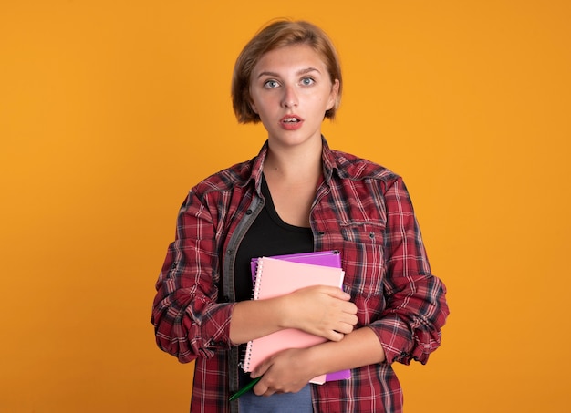 Surprised young slavic student girl holds book and notebook 