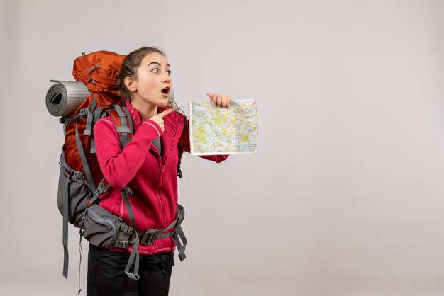 surprised young traveller with big backpack holding up map on grey isolated