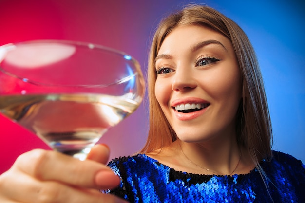 The surprised young woman in party clothes posing with glass of wine