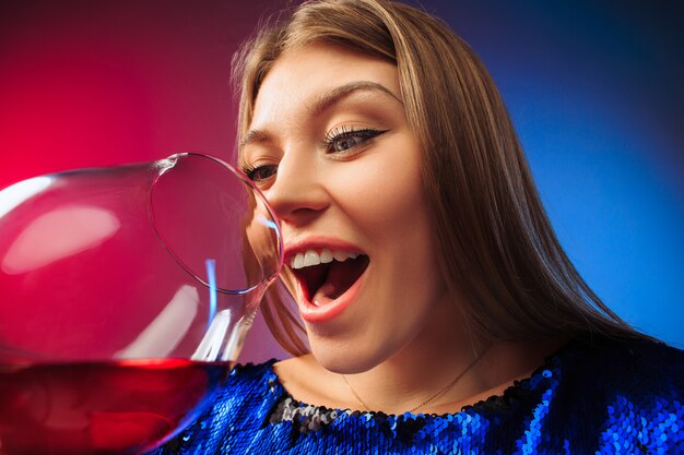 와인 한 잔 함께 포즈 파티 옷에 놀란 된 젊은 여자.