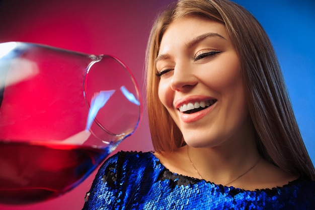 The surprised young woman in party clothes posing with glass of wine.