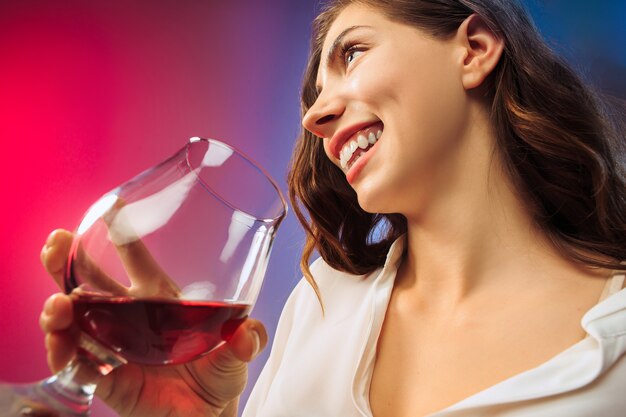 The surprised young woman in party clothes posing with glass of wine.