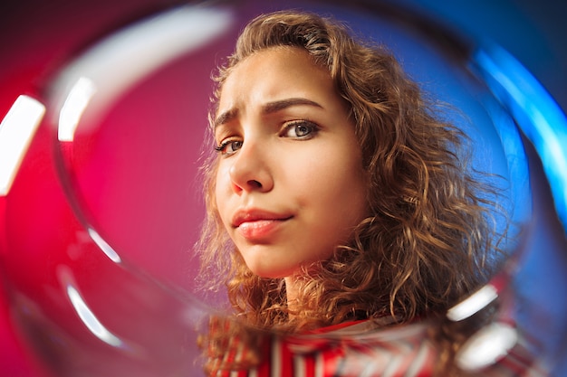 The surprised young woman in party clothes posing with glass of wine.