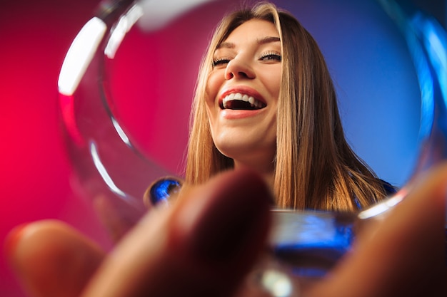 The surprised young woman in party clothes posing with glass of wine.