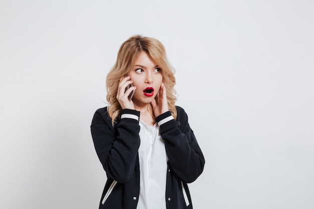 Surprised young woman talking on the phone
