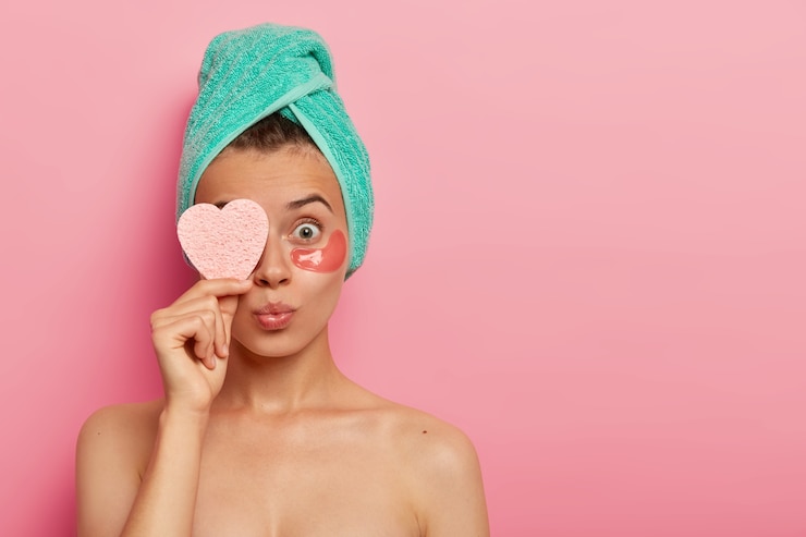 Free Photo surprised young woman wears moisturizing eye patches under eyes, spends time at home, has daily pampering routine, uses modern cosmetics