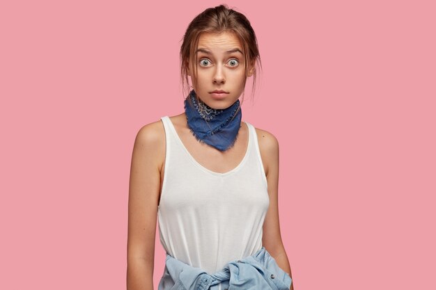 Surprised young woman with glasses posing against the pink wall