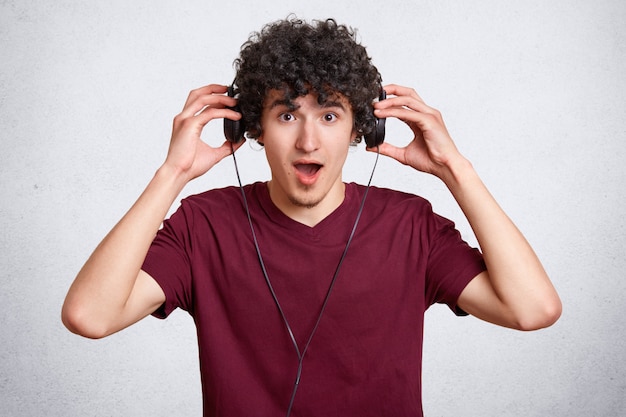 Surprised youngster wears modern headphones