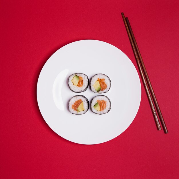 Суши и палочки для еды на красном