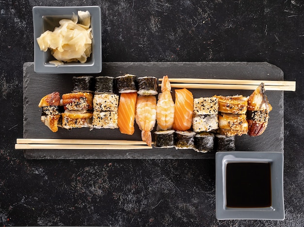 Sushi plate on dark stone next to chopsticks on black background in studio. Healthy asian food