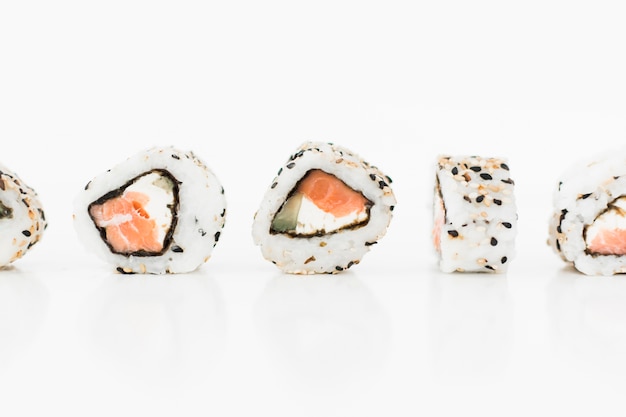 Foto gratuita i sushi rotolano la fila contro fondo bianco