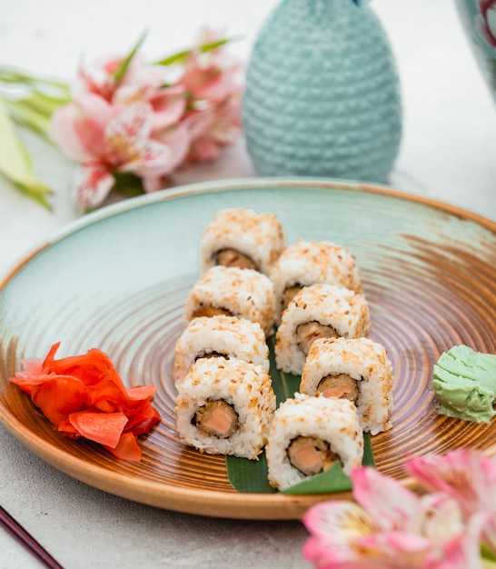 Sushi rolls in brown green plate with ginger and wasabi.