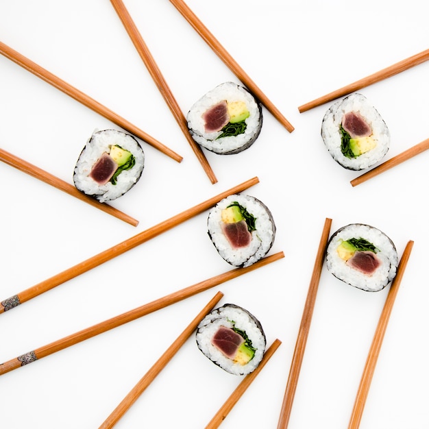 Sushi rolls holded in chopsticks on a white background