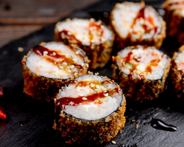 Sushi rolls served with sauce and sesame seeds