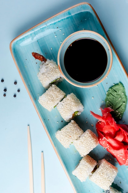 Sushi rolls topped with sesame and side sauce