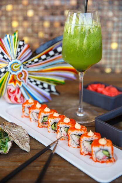 Sushi rolls with red tobiko served with kiwi and green apple cocktail