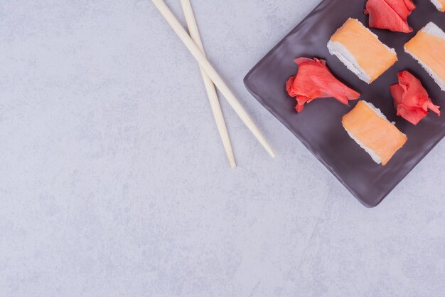 Sushi rolls with salmon in black ceramic platters