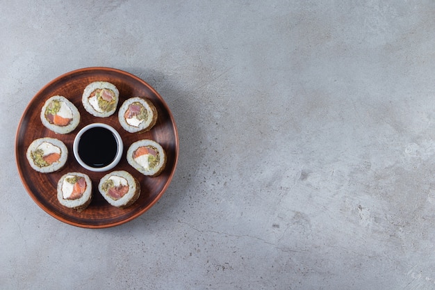 Sushi rolls with soy sauce placed on a wooden plate . 
