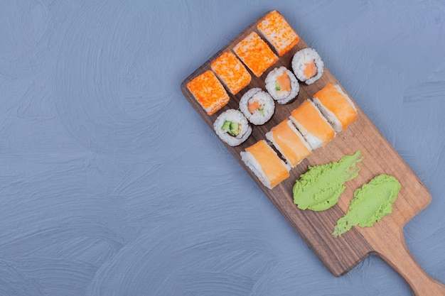 Sushi rolls with wasabi sauce on a wooden platter