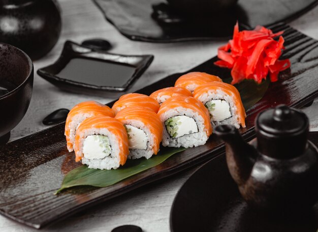 Sushi rolls wrapped with salmon inside black plate.