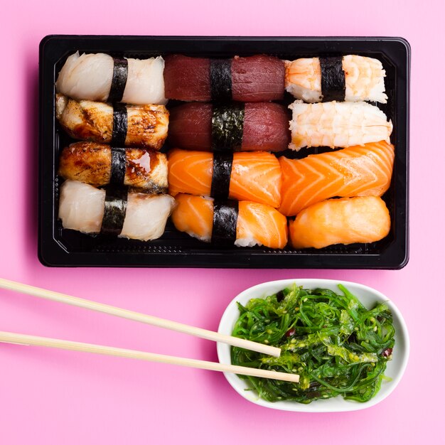 Sushi set box with seaweed salad on a rose background