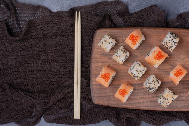 Sushi set. Philadelphia and alaska rolls on wooden plate with chopsticks.