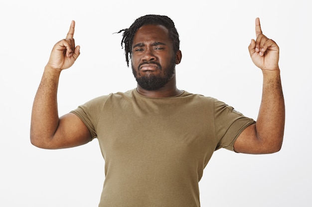 Free photo suspicious guy in a brown t-shirt posing against the white wall