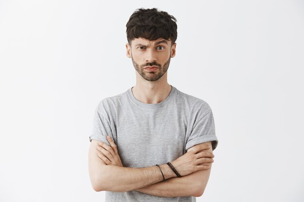 Suspicious handsome guy posing against the white wall