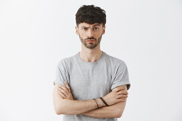 Suspicious handsome guy posing against the white wall