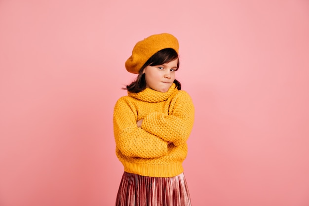  suspicious kid in yellow sweater. Short-haired preteen girl