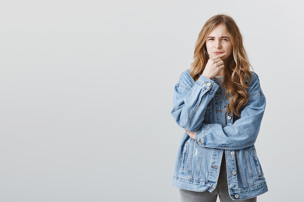 Suspicious thoughtful blond teenage girl thinking, squinting doubtful, making choice