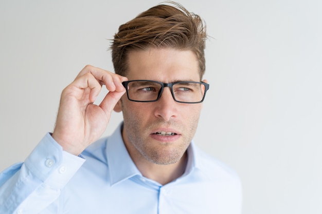 Free photo suspicious young man looking away attentively