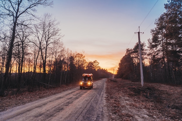 SUV rides on a dirt road at evening