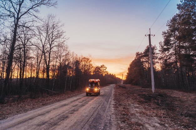 SUV rides on a dirt road at evening