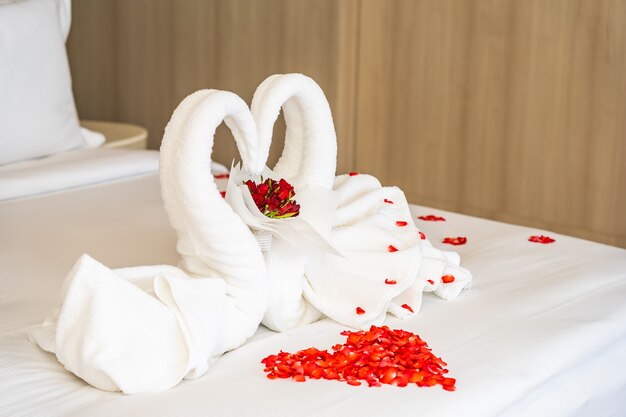 Swan towel on bed with red rose flower petals