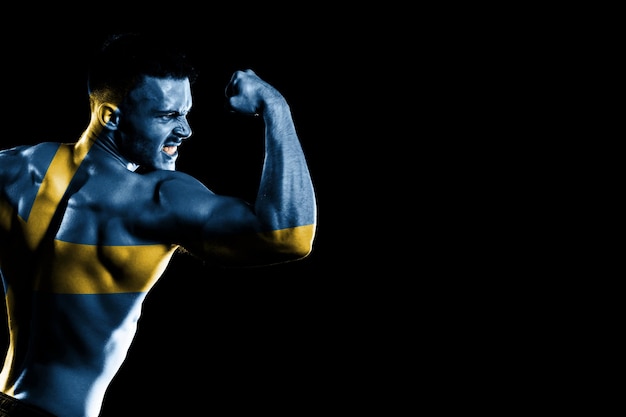 Sweden flag on handsome young muscular man black background