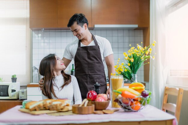 달콤한 아시아 커플의 행복한 순간은 함께 부엌 집 개념에서 아침 식사를 준비합니다.