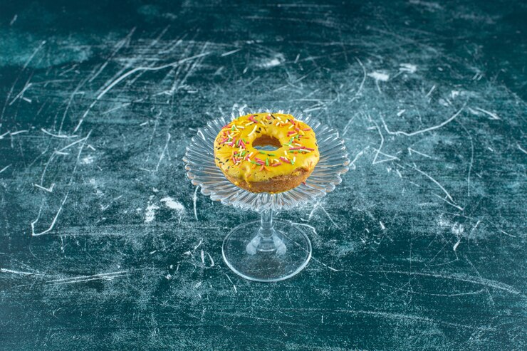 Free Photo sweet bagel covered with chocolate chips on a glass pedestal , on the blue background. high quality photo
