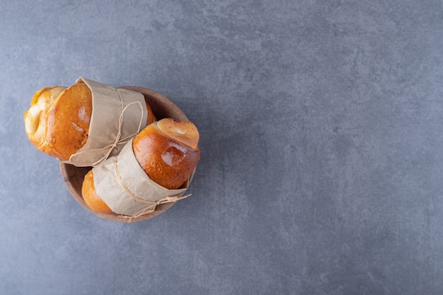 Free photo sweet bun tied with a thread in a bowl on marble table.