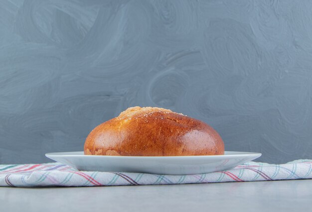 Free photo sweet bun with cloth on white plate.