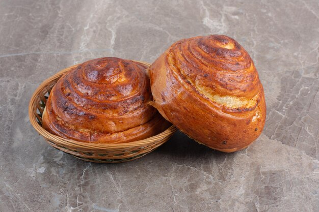 Sweet buns inside and leaning against a small basket on marble background. High quality photo