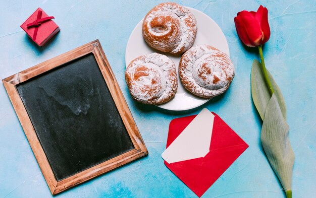 Sweet buns on plate with blank chalkboard