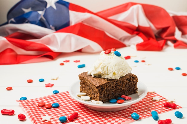 Free photo sweet candies served with cake and ice cream scoop in front of usa flag on white desk