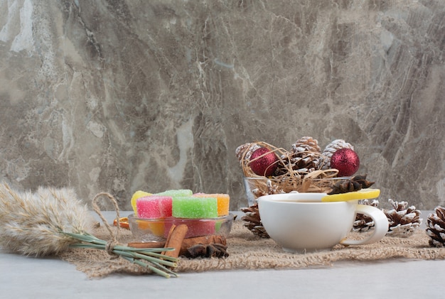 Foto gratuita caramelle dolci con gustosa tazza di tè su tela di sacco. foto di alta qualità