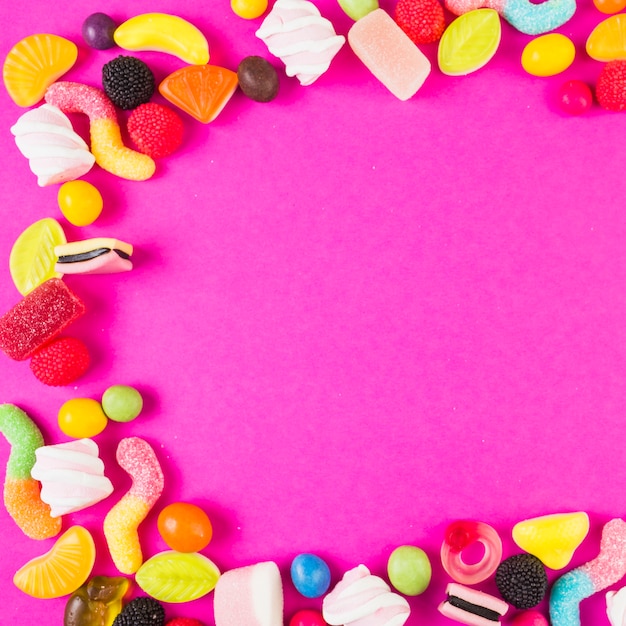 Sweet candies with various shapes on pink background