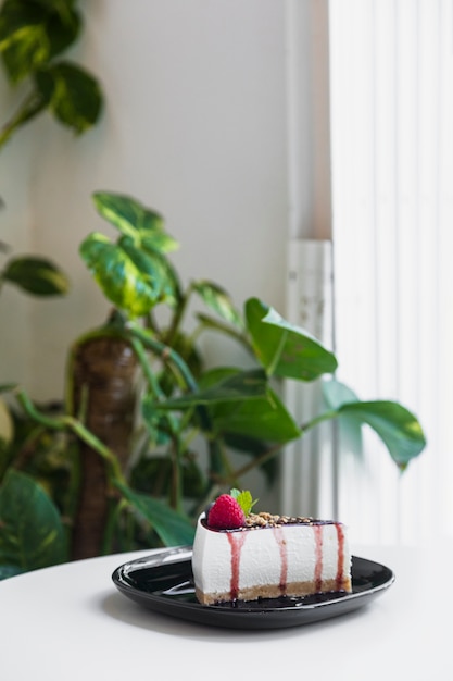 흰색 테이블 위에 검은 세라믹 접시에 신선한 베리와 달콤한 치즈 케이크