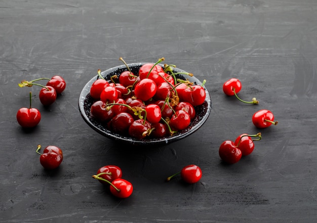 Sweet cherries in a black plate high angle view on a grey table