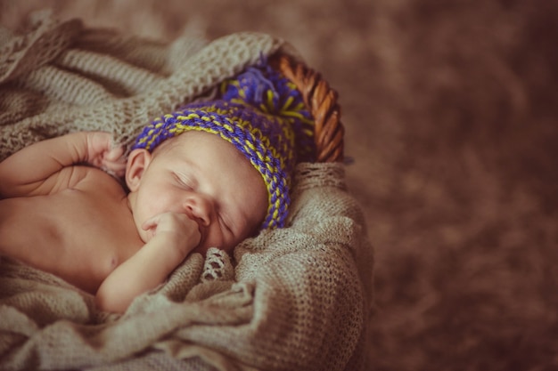 Sweet child in woolen hat sleeps in the basket