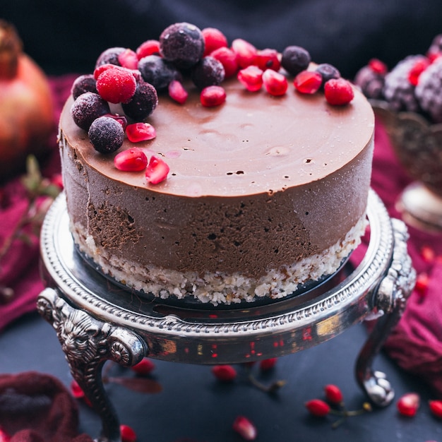 Sweet chocolate cake with pomegranate seeds and fresh berries on it