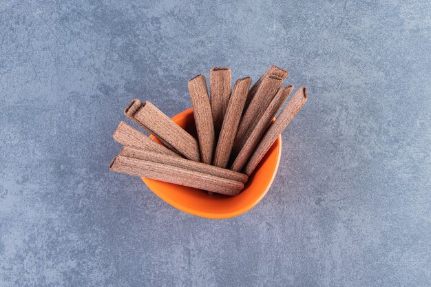 Sweet chocolate wafer roll in a bowl, on the marble background.